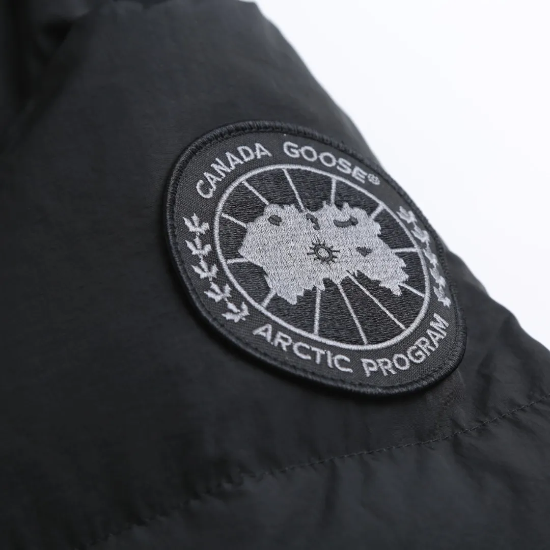 P980 Canada Goose hooded down jacket Fabric selection: Weaved with 400T high-count yarn. After special water-repellent treatment, the surface forms a lotus leaf effect - raindrops will slide down in beads, and snow particles will fall off when touched. The tear resistance reaches 200N (approximately 20kg load-bearing), the light gray matte texture breaks the stereotype of "outdoor clothing = hardcore", and the soft luster presents a high-end matte effect under urban neon lights, seamlessly switching scenes from ski resorts to CBD office buildings.  Process 1: Use polyester woven ribbons as the base, and use high-precision computer embroidery to decorate the brand letters on the ribbons. The edges of the pattern are clear, the stitches are fine and even, and multiple layers of embroidery threads are stacked to enhance the three-dimensional effect.  Process 2: Precision thread reinforcement to prevent velvet drilling and ensure that the fluffy and resilient elasticity lasts as new.  Details: The embedded cuffs are three-dimensionally woven to form a "wavy" elastic structure, forming natural folds when fitting the wrist, increasing the contact area with the skin, thus improving the windproof effect. At the same time, micro-velvet treatment is added to the inside of the cuffs, which feels like a second layer of skin and avoids friction on the skin from metal zippers or hard fabrics.  90 national standard high-quality white duck down: selected high-loft down, weighing 240g, light and warm, with excellent temperature locking performance and good resilience.  Accessories: 1:1 customized armband, 1:1 customized zipper pendant, 1:1 customized elastic buckle, etc. SIZE: S M L XL